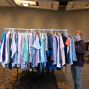 A student is looking at a rack full of button-ups at the Smokey's Closet Pack to Give Back event that took place in the Student Union.