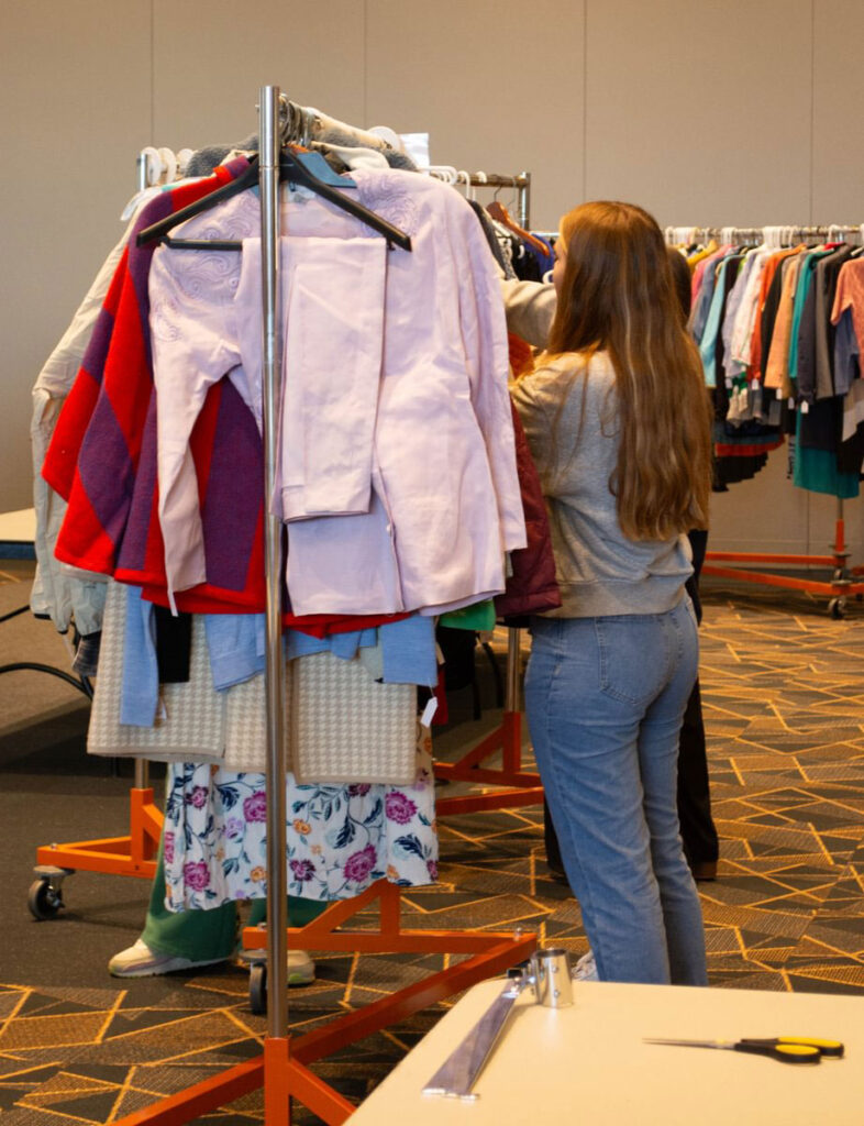 A student looking at a rack of women's clothing during Smokey's Closet Pack to Give Back event