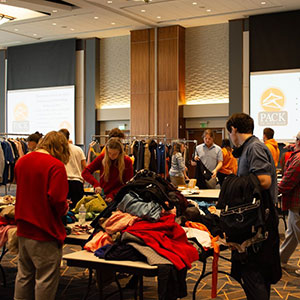 A variety of students sorting through clothes on tables within the Student Union