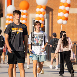 A student smiles while walking across the Ped walkay bridge during the first day of Fall classes on August 23, 2023. Photo by Steven Bridges/University of Tennessee. 