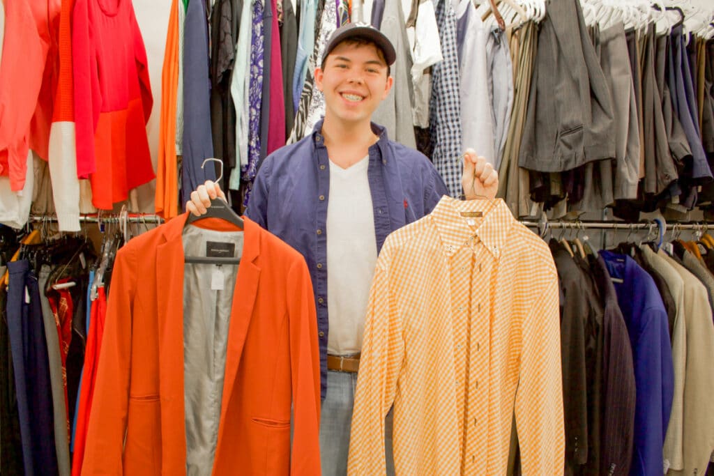 An RA holds up a shirt and suit jacket.