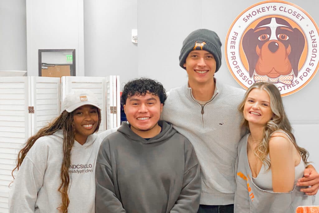 Students smile in front of a Smokey's Closet Sign.