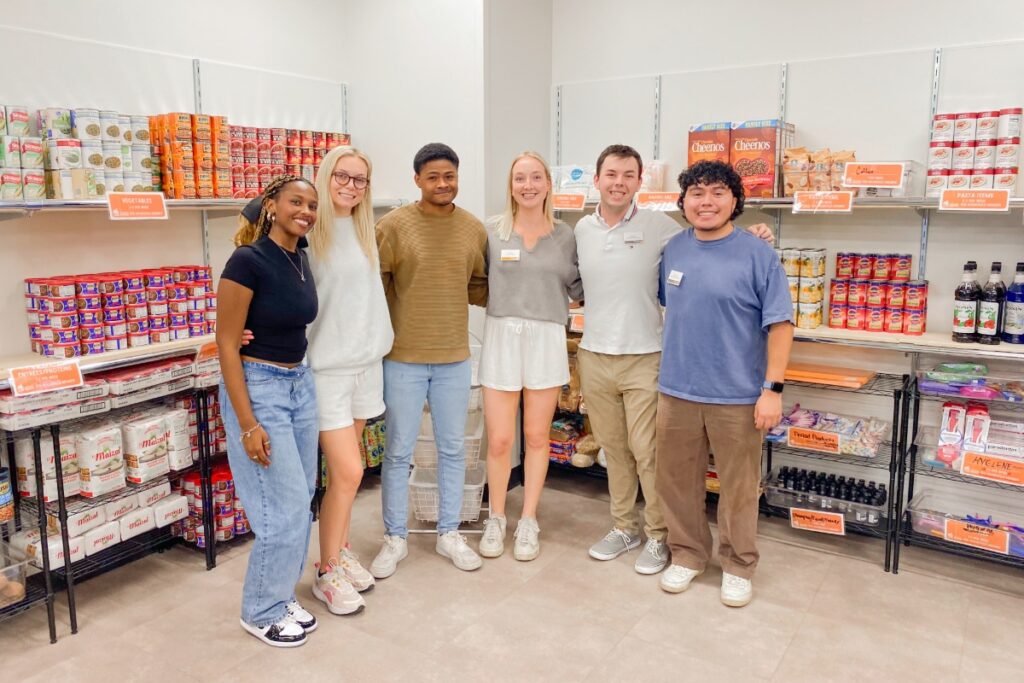Students smile in front of food shelves.