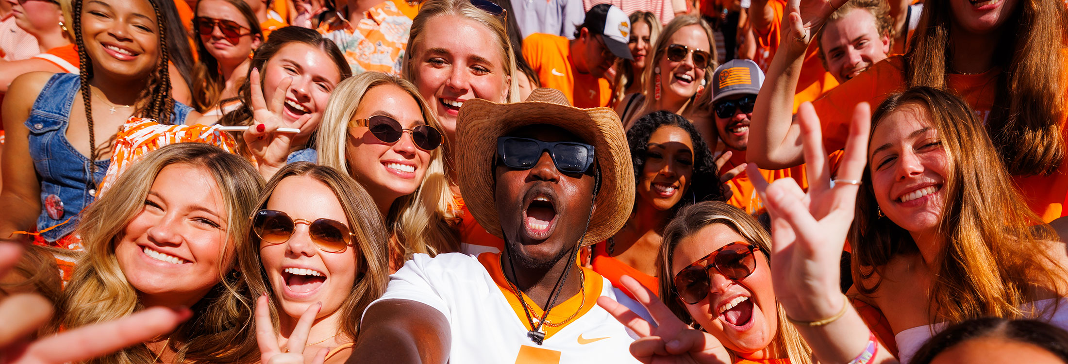 Students cheer in the student section of Neyland Stadium on a sunny day.