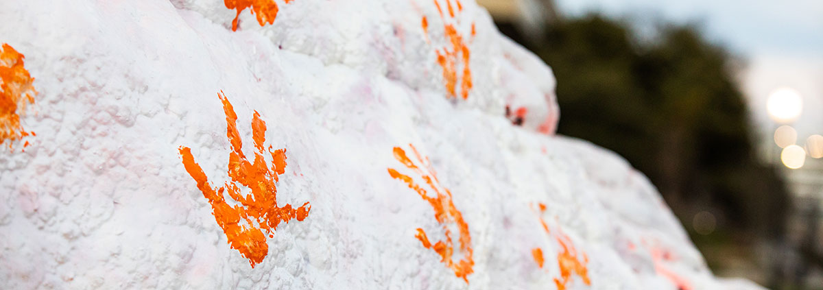Orange handprints on the Rock that is painted white.