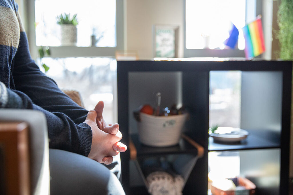 Someone in a single therapy session. It is a close up of their fingers intertwined.