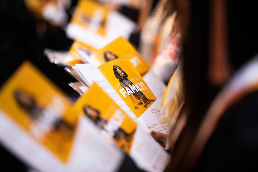A Welcome to the Family ad with Smokey inside the program as graduates sing the Alma Mater during the College of Social Work Commencement Ceremony at Thompson-Boling Arena on May 20, 2022.