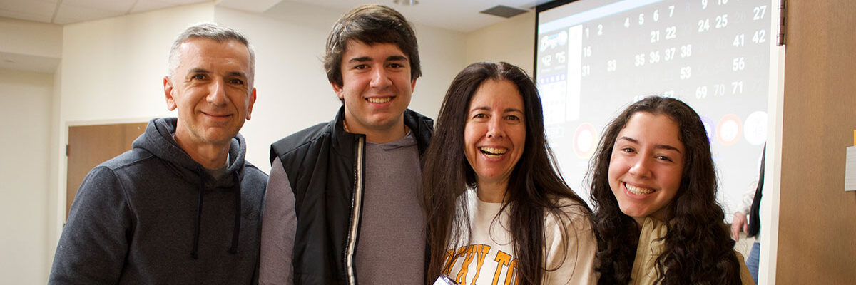 A family attending the Bingo event during Spring Family Reunion. They are all smiling together.