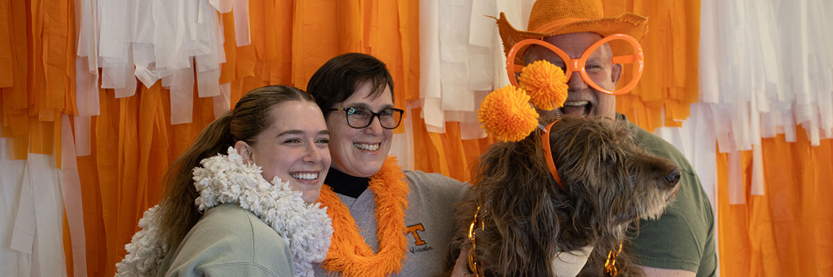 A family is pictured in front of an orange and white backdrop during Spring Family Reunion.