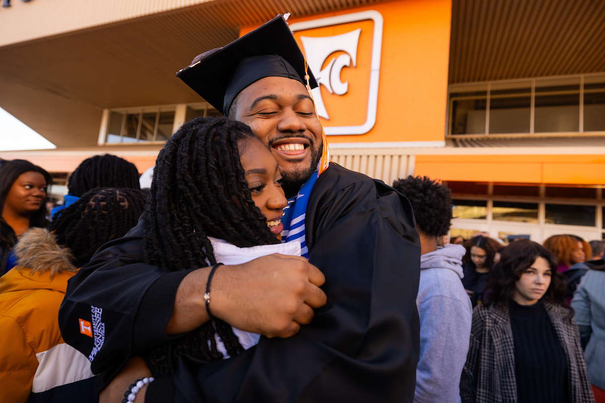 Two siblings hugging each other outside of Thompson Bowling Arena after a commencement ceremony. 