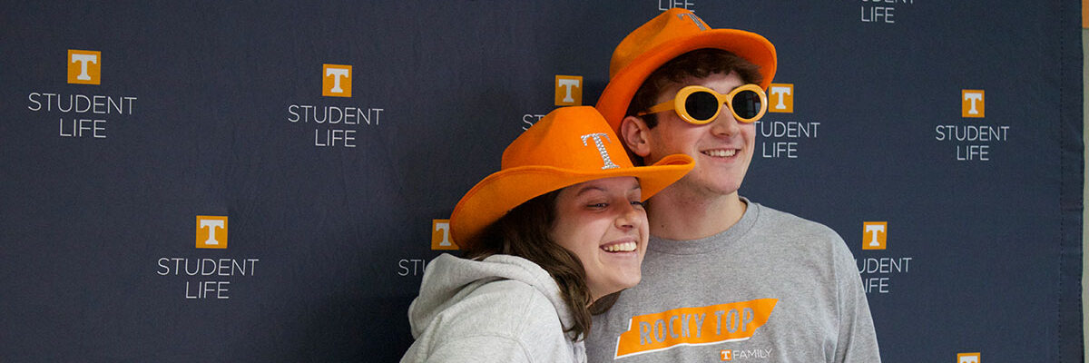A brother and sister are smiling at a Student Life photobooth during a family event on campus.