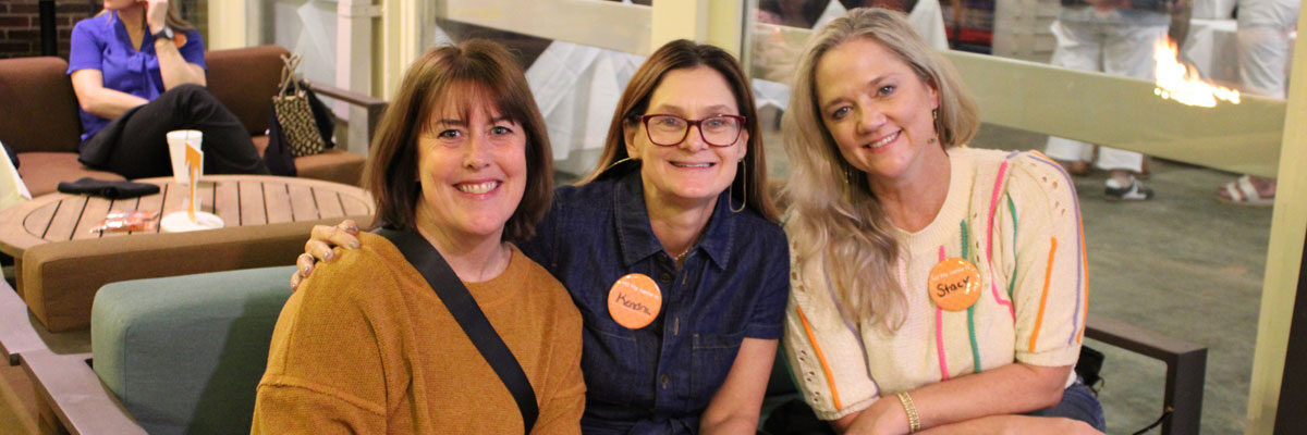 Three Volunteer parents are gathered around a table outside at a Vol Family Social event in Nashville, Tennessee.