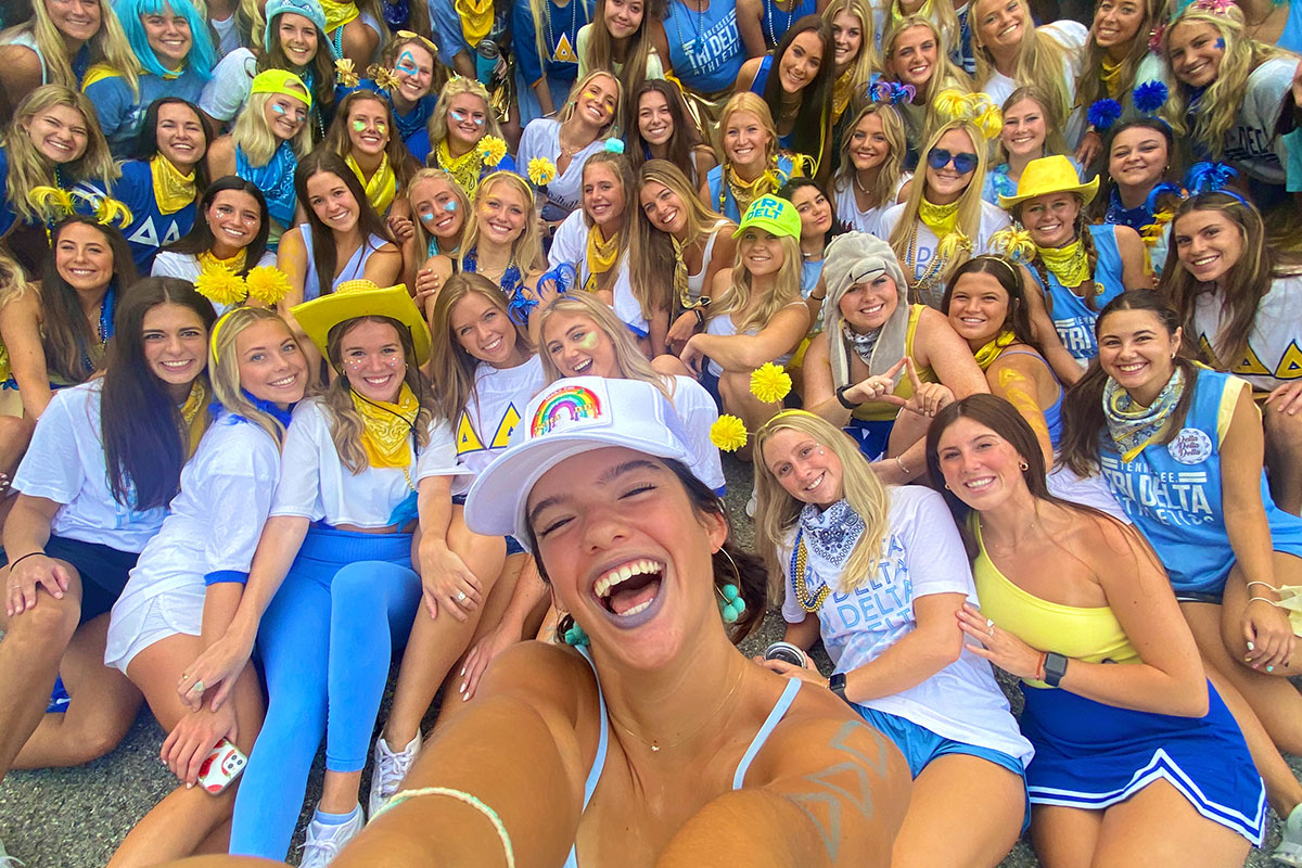 Members of Delta Delta Delta during work week in Sorority Village. They are all dressed in blue, yellow, and white outfits to show their sorority pride.