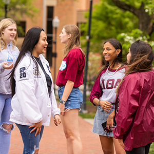 Two members of Lambda Theta Alpha Sorority, Inc. with another member of the Multicultural Greek Council. They are on the path leading to Andy Holt Tower in Circle Park.