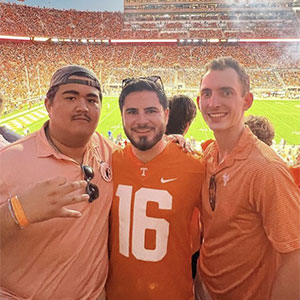 Three members of Beta Theta Pi in Neyland Stadium. The football field is in the background.