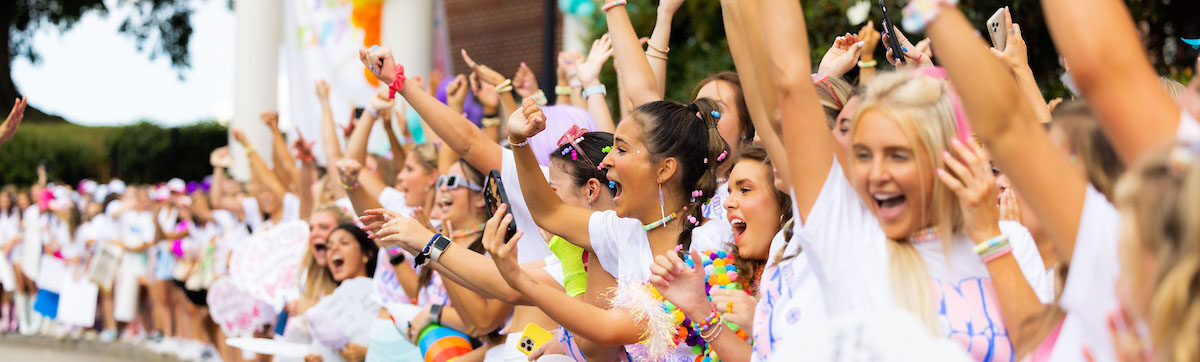 Various sorority members outside of their sorority house on bid day in 2022. They are waiting expectantly for the potential new members to run to their new sorority.