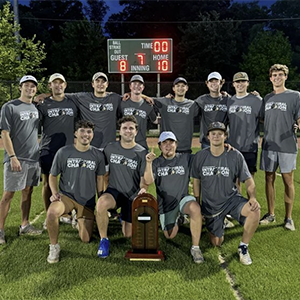 Members of Sigma Alpha Epsilon after winning in the intramural championship. They are posing with their champion trophy, and their dark grey intramural champion shirts.
