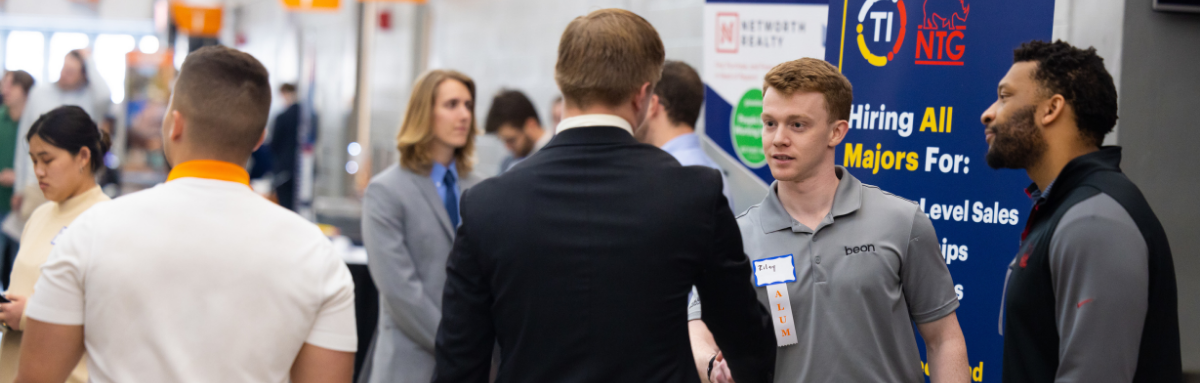 Employer shakes hand with student at career fair.