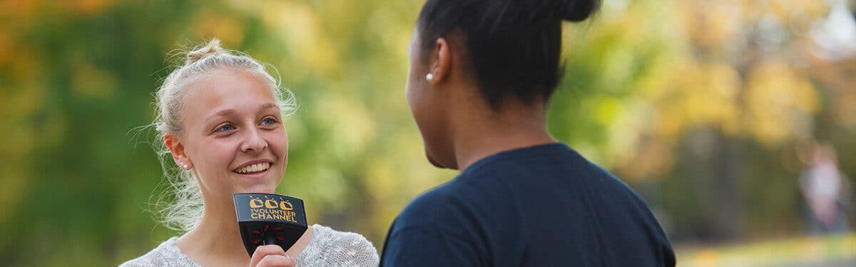 a student holds a microphone while speaking to another student