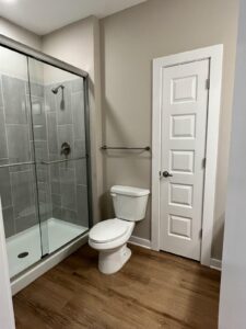 The bathroom with a linen closet, toilet and walk in shower with a glass door