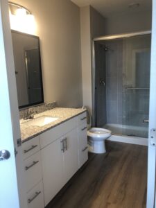 The bathroom with a walk in glass door shower, toilet and built in cabinets