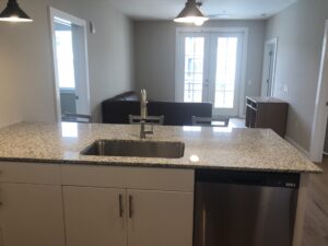 A view of the kitchen island overlooking the living room and the two french doors leading to the balcony