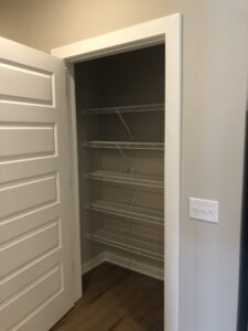 An empty kitchen utility closet with stacked metal shelving