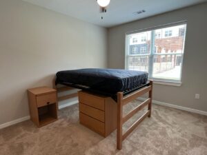 An undecorated bedroom that has one lofted bed, two nightstands and one dresser