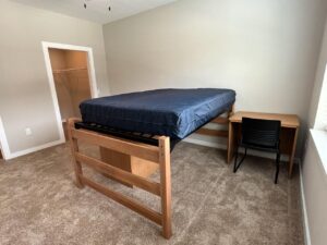 An undecorated bedroom that has one lofted bed, two nightstands and one dresser