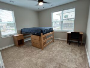 An undecorated bedroom that has one lofted bed, two nightstands and one dresser