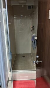 The shower in North Carrick, Reese Hall, South Carrick that has a towel rack and a red mat outside