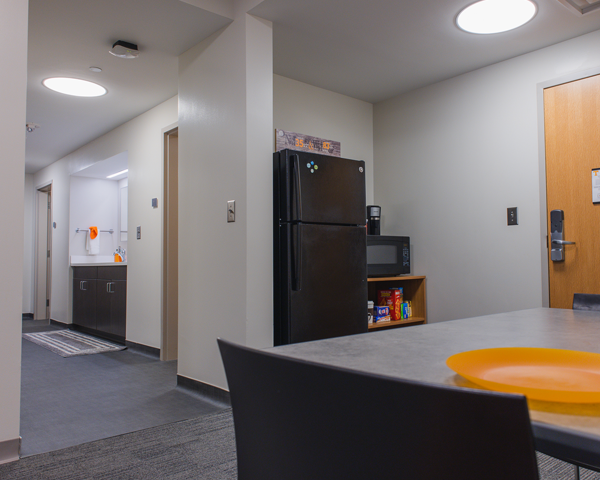 The kitchen area in Stokely that looks beyond the dining table to the refrigerator and the communal bathroom sink in the back