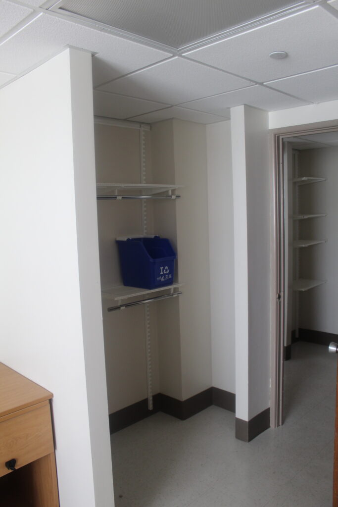 The built in closets with a recycling bin on the shelf