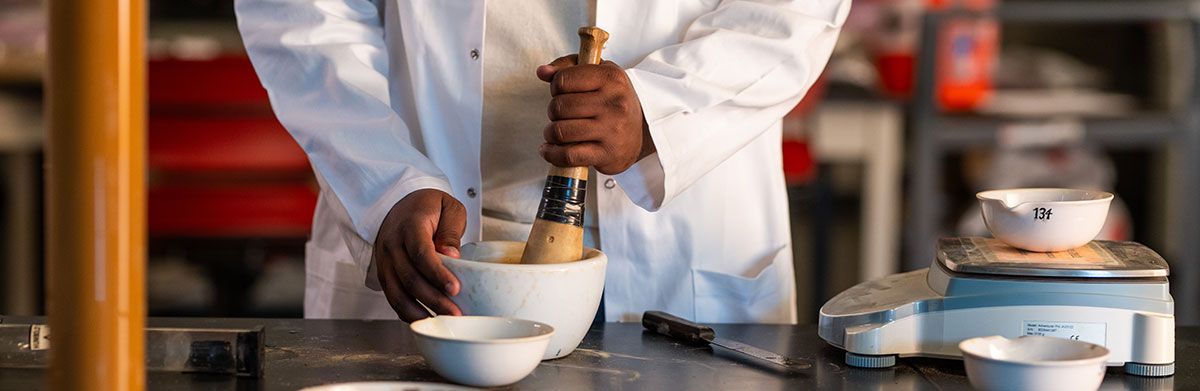 A closeup of an engineering student working with a mortar and pestle in the Tickle College of Engineering soil lab