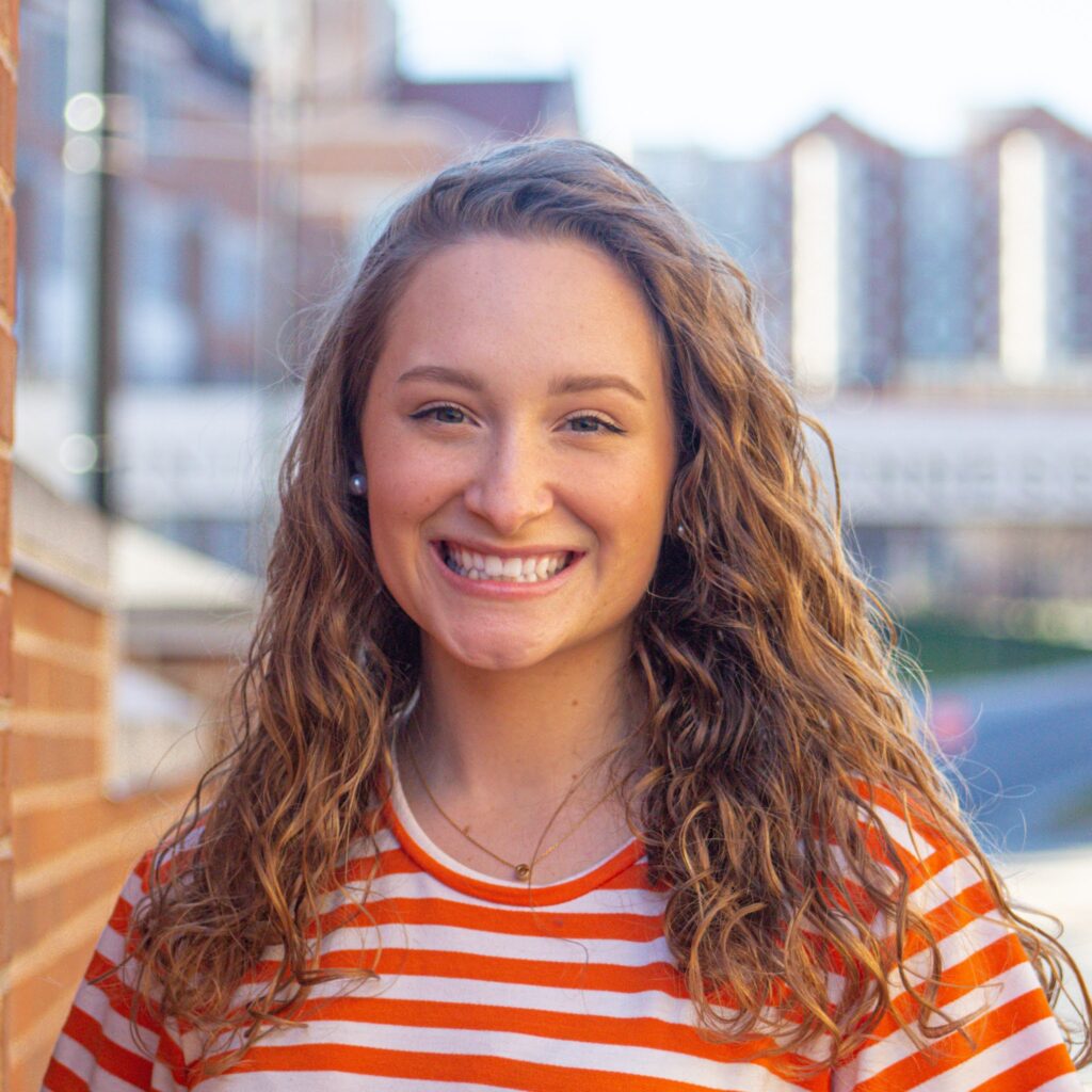 Student smiling in an orange and white striped shirt