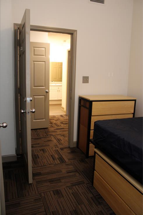 Empty room in Vol Hall showing an open door, a dresser, and the corner of a bed.