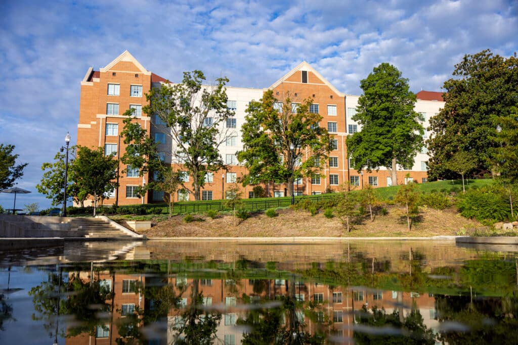 exterior photo of a building, Popular Hall, with a pond and trees in front of it