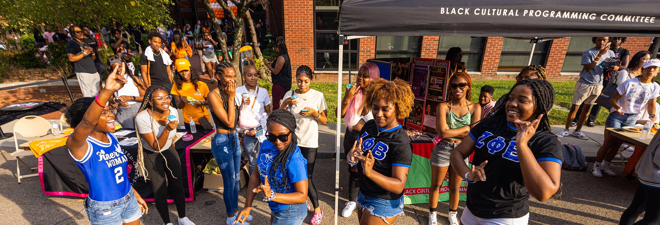 Students dancing in front of a student organization fair display.