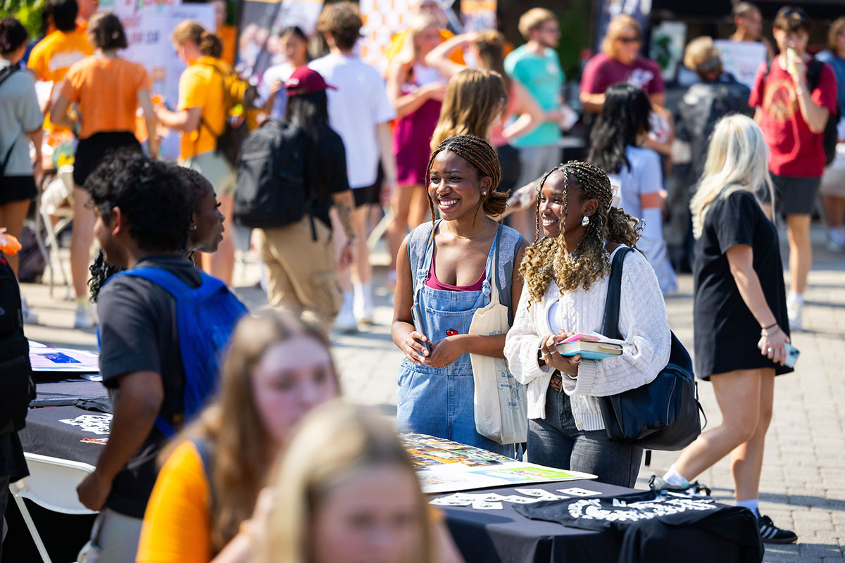 Student smiling at club table during Student Engagement Fair.