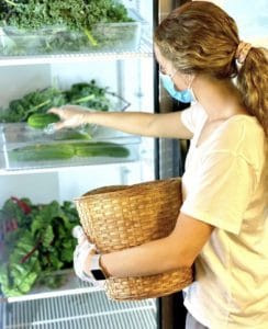 Student putting veggies in a fridge