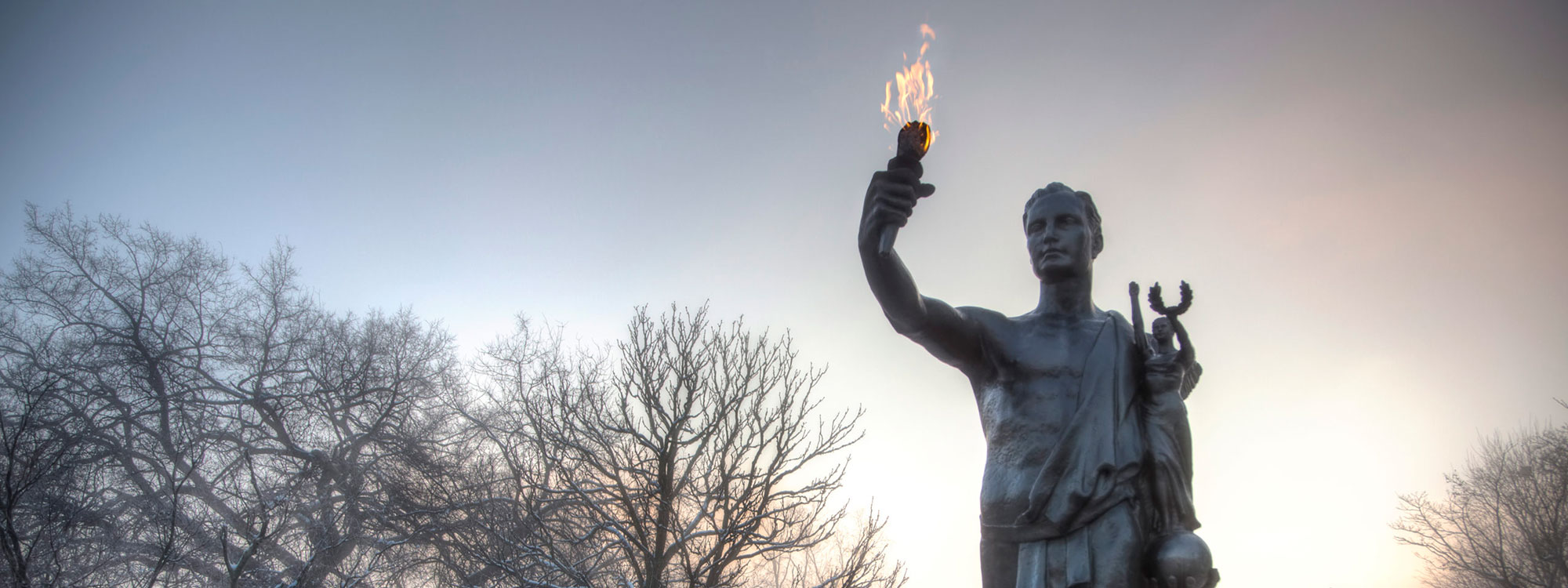 The Torchbearer with a hazy winter sky, lit from behind.