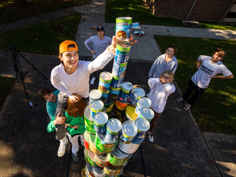 Students stack donated canned foods into a tower