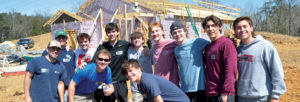 Group photo of student volunteers posing in front of the Habitat for Humanity house.