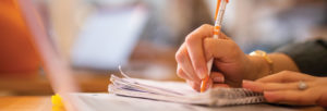 A student writes notes in a notebook