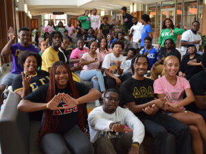 Members of NPHC fill the Student Union atrium, posing with their hand signs