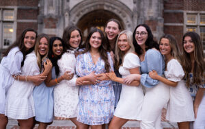 Presidents of Panhellenic organizations lean into a pose in front of historic Ayres Hall, wearing coordinating white and light blue attire