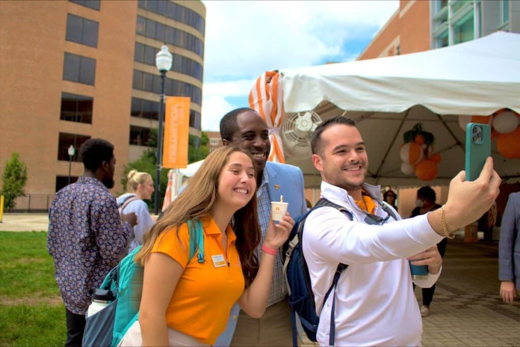 Three individuals taking a selfie with a milkshake.