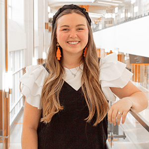 Picture of an individual in the Student Union with orange earrings and a black headband and long auburn hair