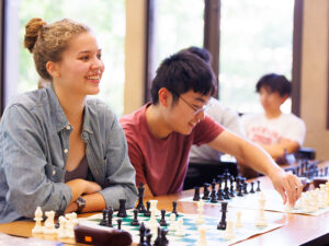 Students smile while playing chess.