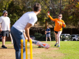 Students play cricket in Circle Park on a sunny day.